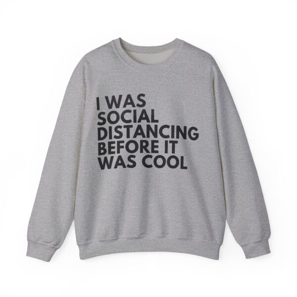 Black casual sweatshirt with humorous quote "I was social distancing before it was cool" in bold text. Perfect for a laid-back, trendy look.